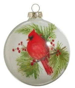 Ornement en forme de boule en verre. Cardinal sur une branche de pin.